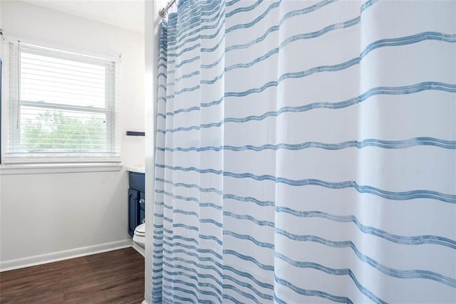 full bath featuring wood finished floors, baseboards, vanity, and curtained shower