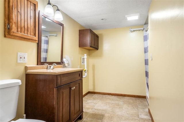 full bath with toilet, baseboards, vanity, and a textured ceiling