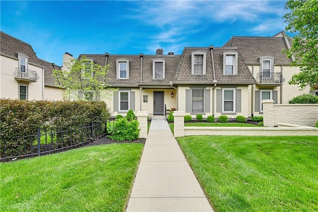 view of front of home featuring a shingled roof, mansard roof, and a front yard