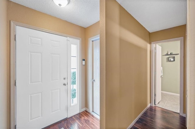 entrance foyer featuring dark wood-style flooring, baseboards, and a textured ceiling