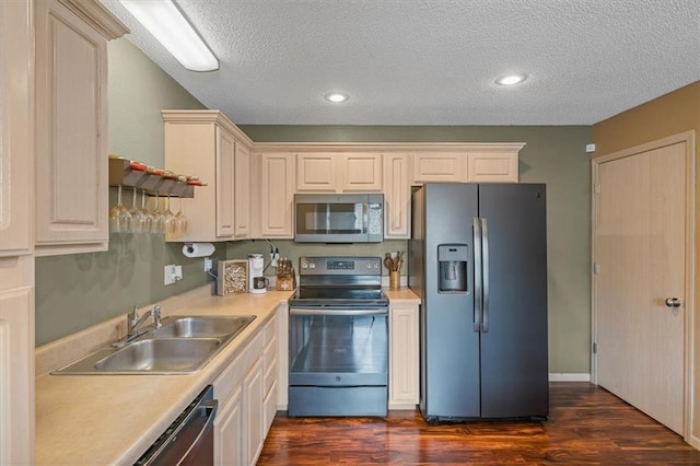 kitchen with dark wood-style flooring, a textured ceiling, a sink, light countertops, and stainless steel appliances