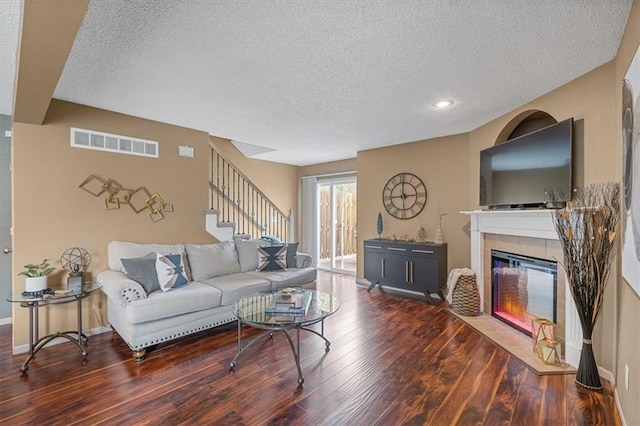 living area featuring visible vents, a textured ceiling, stairs, and wood finished floors