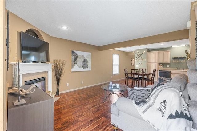 living room featuring recessed lighting, baseboards, a glass covered fireplace, and dark wood-type flooring