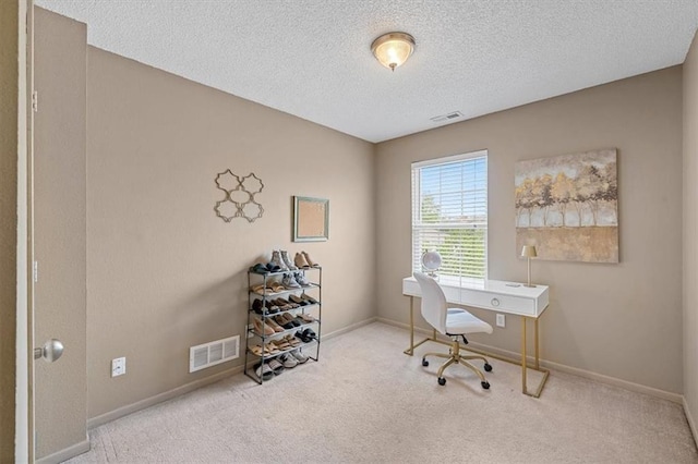 carpeted office with visible vents, a textured ceiling, and baseboards