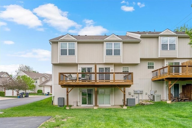 rear view of house featuring a lawn, central AC unit, and a deck