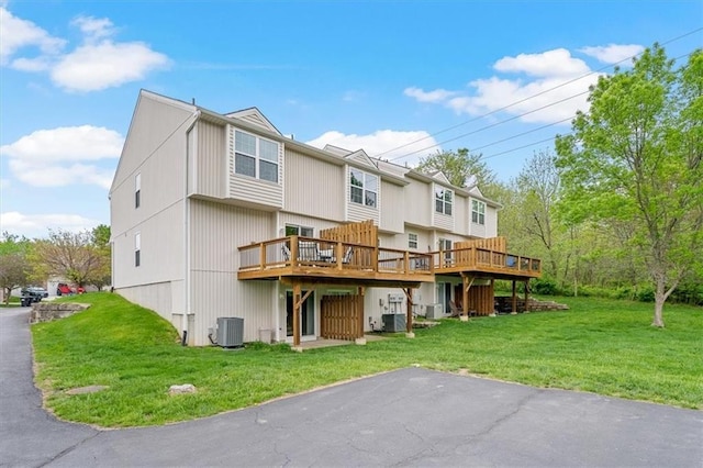 rear view of property featuring a lawn, a wooden deck, and cooling unit