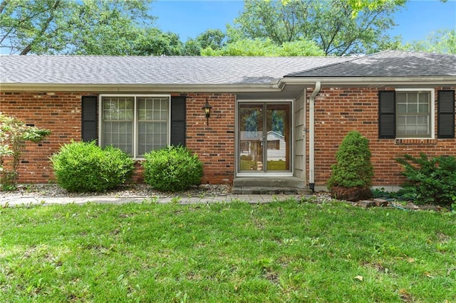 2217 Kingman St, Leavenworth, KS 66048 - doorway to property with brick siding, a lawn, and a shingled roof
