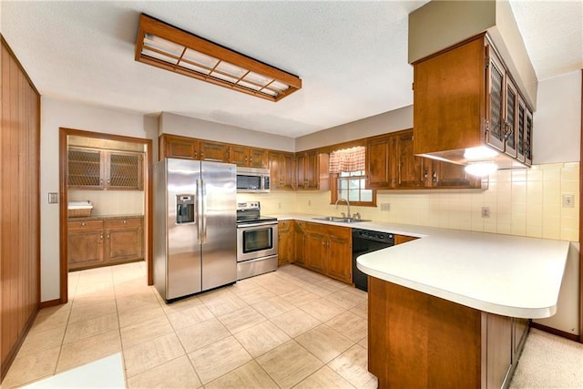 2217 Kingman St, Leavenworth, KS 66048 - kitchen featuring stainless steel appliances, a peninsula, light countertops, brown cabinets, and backsplash
