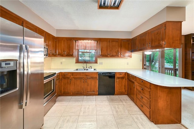 2217 Kingman St, Leavenworth, KS 66048 - kitchen with appliances with stainless steel finishes, a peninsula, light countertops, backsplash, and a textured ceiling