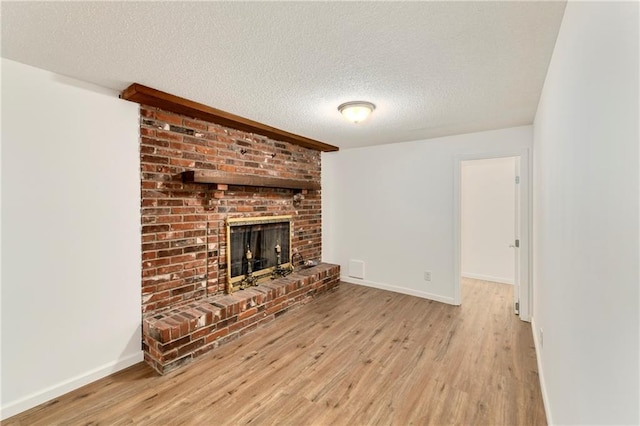 2217 Kingman St, Leavenworth, KS 66048 - unfurnished living room with wood finished floors, a textured ceiling, and a brick fireplace