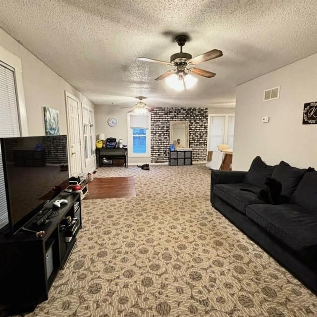 living room featuring visible vents, a textured ceiling, carpet, and ceiling fan
