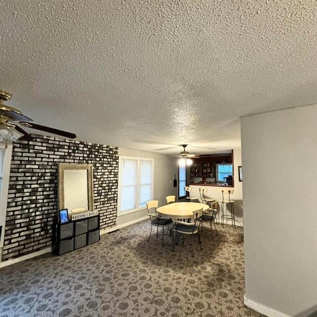 carpeted dining room with a ceiling fan, baseboards, and a textured ceiling
