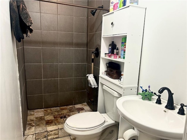 full bathroom with a sink, a shower stall, stone finish flooring, and toilet