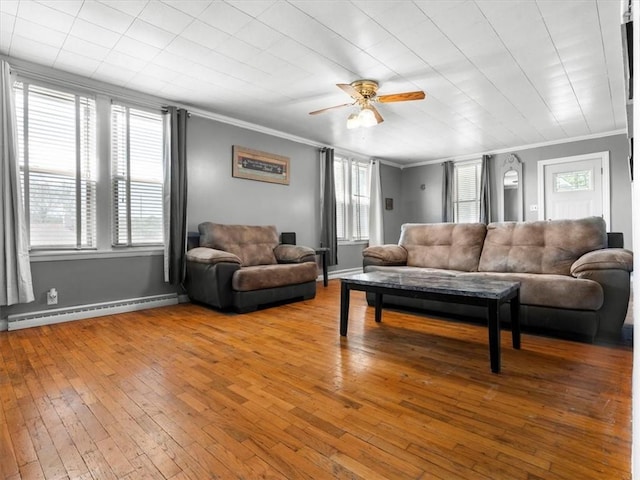 living area featuring a baseboard heating unit, ornamental molding, hardwood / wood-style flooring, plenty of natural light, and a ceiling fan