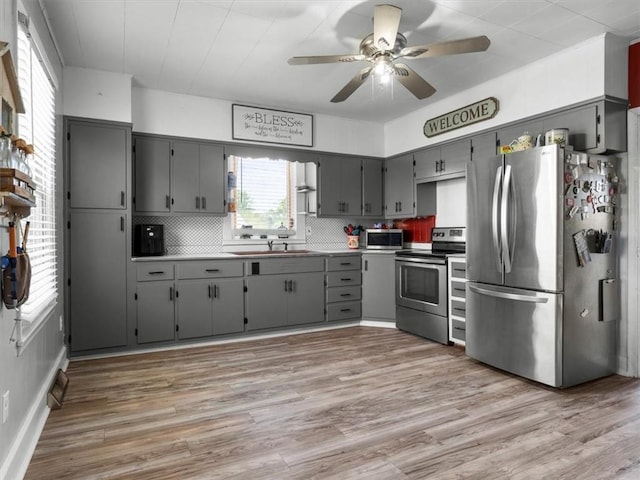 kitchen featuring appliances with stainless steel finishes, gray cabinetry, and a sink