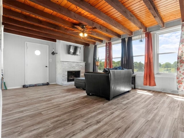 living area featuring a fireplace, beam ceiling, wood finished floors, wood ceiling, and baseboards
