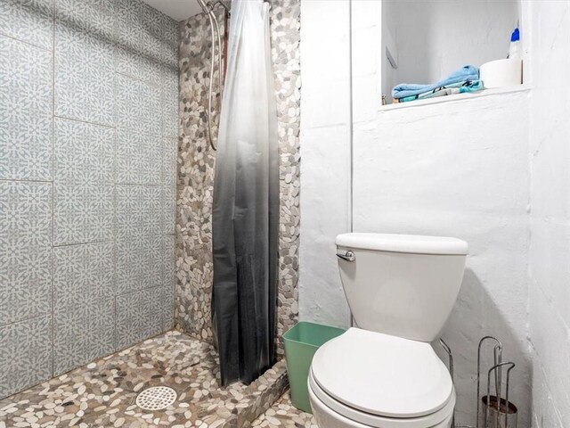 full bath with a tile shower and toilet