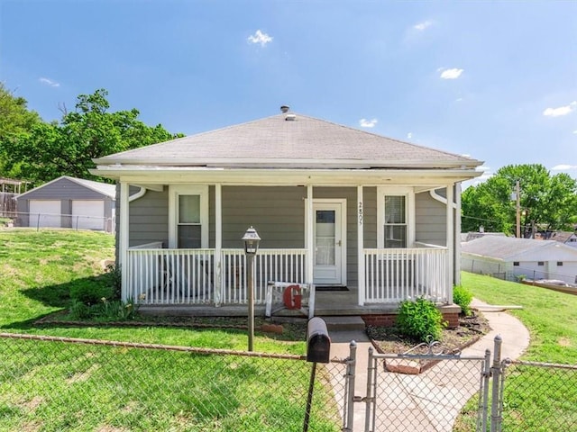 view of front facade with covered porch, roof with shingles, a detached garage, and a gate
