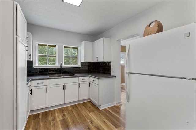 628 S Mulberry St, Ottawa, KS 66067 - kitchen featuring freestanding refrigerator, a sink, dark countertops, light wood-type flooring, and a textured ceiling