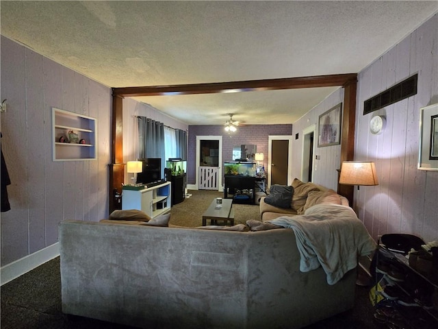 living area with wooden walls, a ceiling fan, a textured ceiling, and baseboards