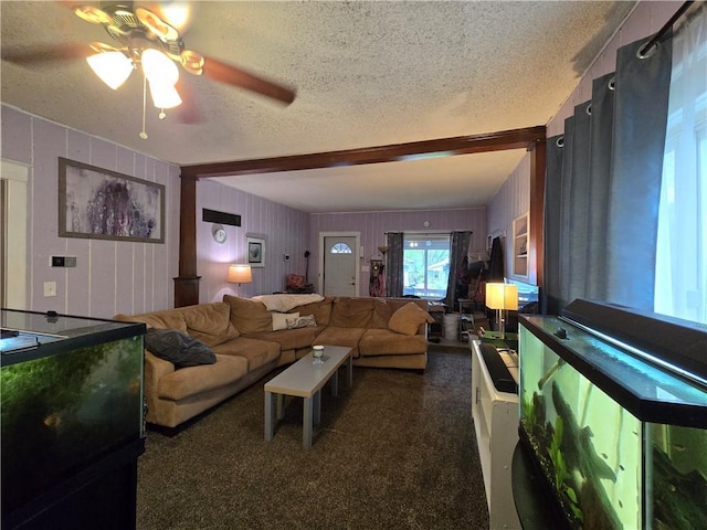 living area featuring carpet floors, a textured ceiling, ceiling fan, and beamed ceiling
