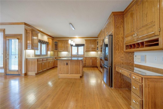 4411 N Mulberry Dr, Kansas City, MO 64116 - kitchen with wall chimney range hood, stainless steel fridge, brown cabinetry, light wood-style flooring, and a kitchen island