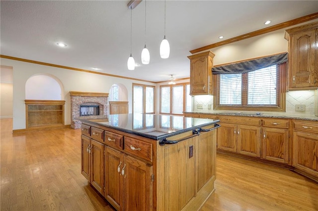 4411 N Mulberry Dr, Kansas City, MO 64116 - kitchen with light wood-style flooring, a brick fireplace, a kitchen island, and tasteful backsplash