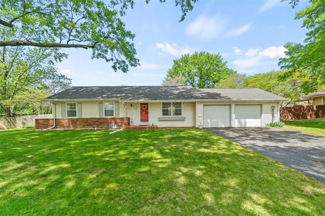 ranch-style home featuring fence, an attached garage, a front yard, and aphalt driveway