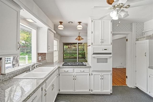 kitchen featuring oven, light countertops, black electric cooktop, white cabinetry, and a sink
