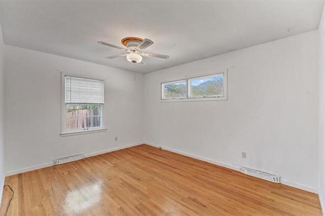 spare room with visible vents, light wood finished floors, ceiling fan, and baseboards