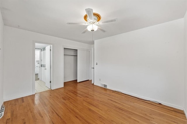 unfurnished bedroom with ceiling fan, a closet, light wood finished floors, and visible vents