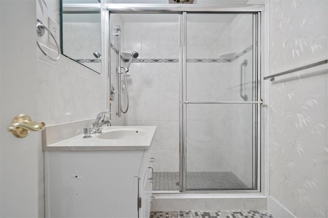full bath featuring vanity, baseboards, and a shower stall
