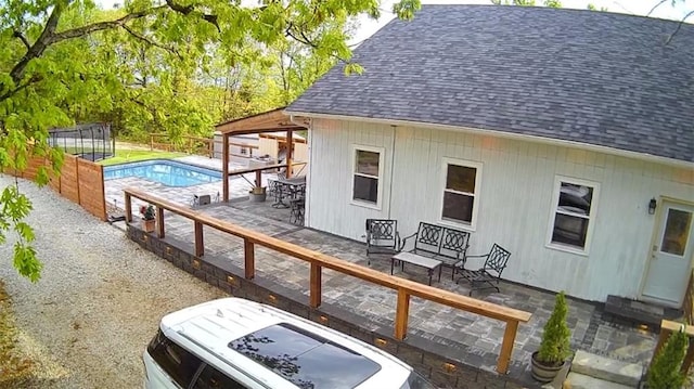 exterior space with a shingled roof, an outdoor pool, and a patio area