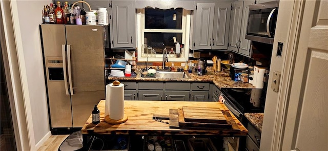 kitchen featuring a sink, butcher block countertops, gray cabinets, stainless steel appliances, and wood finished floors