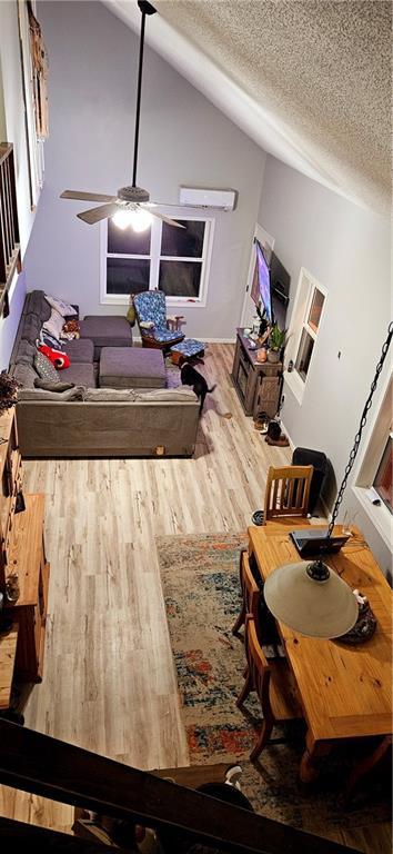 dining space featuring a textured ceiling, ceiling fan, wood finished floors, and lofted ceiling