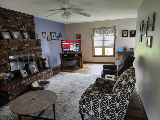 living room with a ceiling fan, baseboards, wood finished floors, and a fireplace