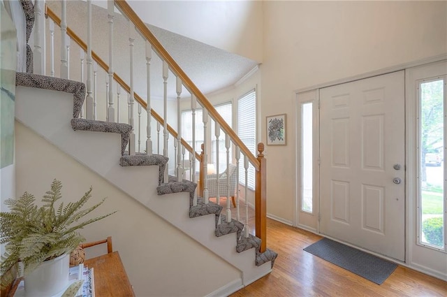 foyer with stairs, a wealth of natural light, and wood finished floors