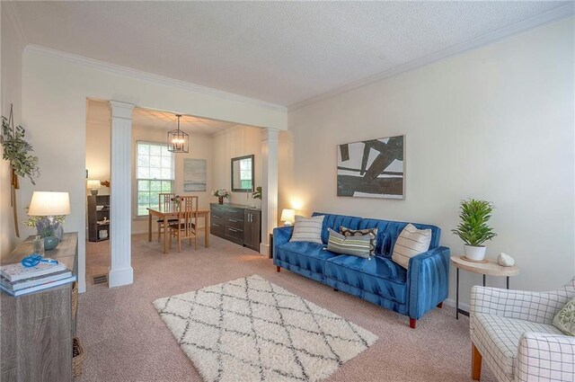living area featuring crown molding, ornate columns, and light colored carpet