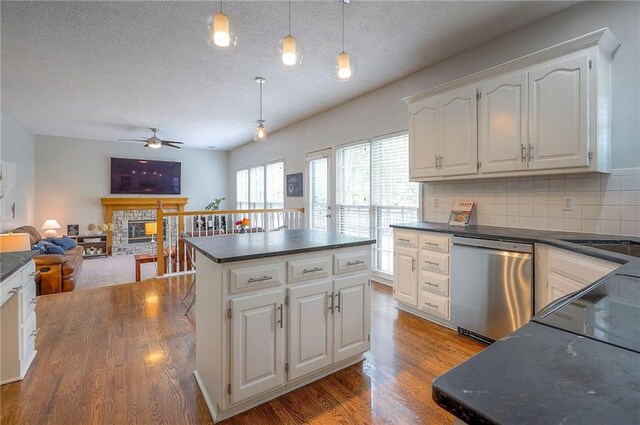 kitchen with dark countertops, a ceiling fan, decorative light fixtures, wood finished floors, and stainless steel dishwasher