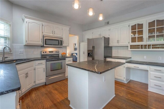 kitchen featuring dark countertops, white cabinetry, tasteful backsplash, a sink, and stainless steel appliances