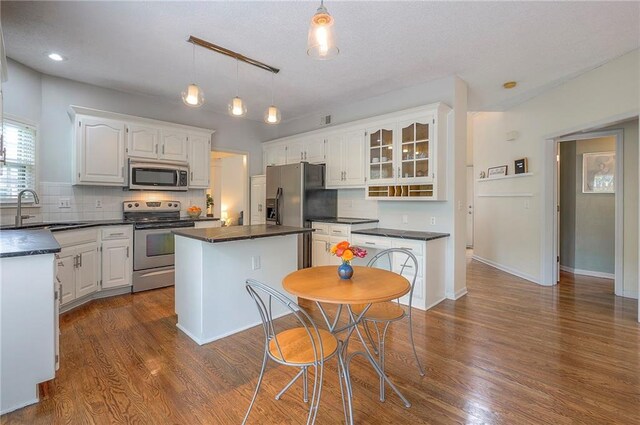 kitchen with a sink, dark countertops, a kitchen island, and stainless steel appliances
