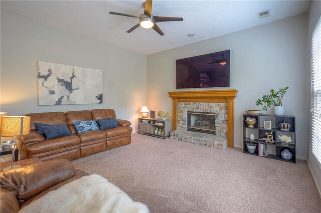 carpeted living room featuring a ceiling fan, a stone fireplace, and visible vents
