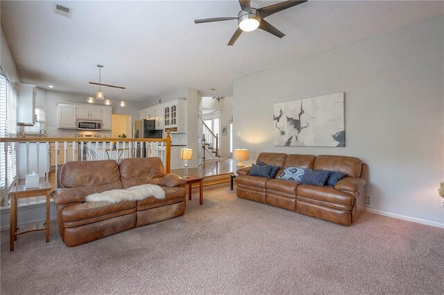 carpeted living room featuring a healthy amount of sunlight, baseboards, a ceiling fan, and visible vents