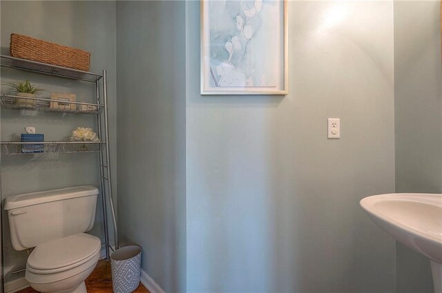 bathroom with toilet, baseboards, and a sink