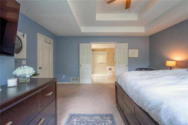 bedroom featuring visible vents, light carpet, baseboards, a raised ceiling, and a ceiling fan