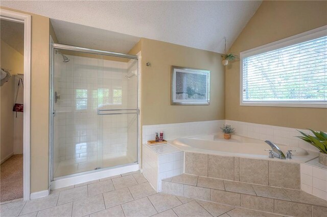 full bath with a garden tub, tile patterned flooring, lofted ceiling, a textured ceiling, and a stall shower