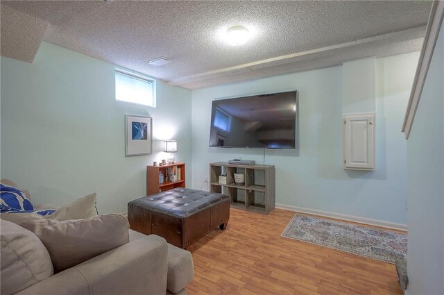 living area with baseboards, light wood finished floors, and a textured ceiling