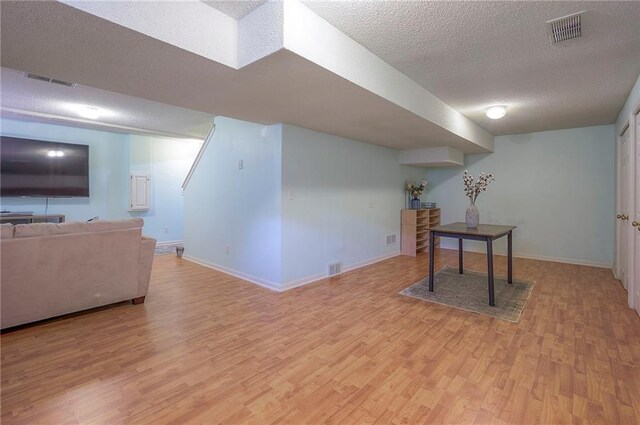 interior space with visible vents, a textured ceiling, light wood finished floors, and baseboards
