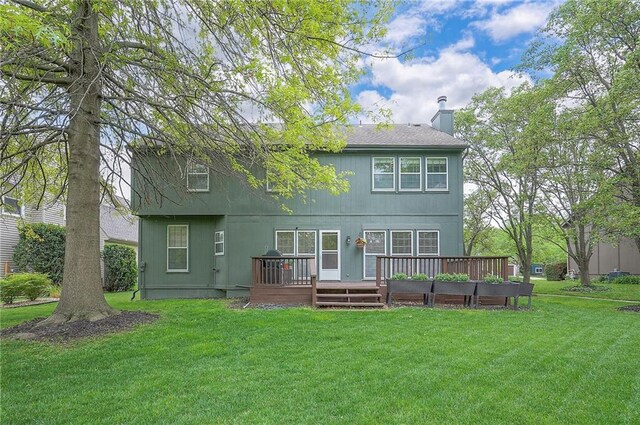 rear view of property featuring a lawn, a deck, and a chimney