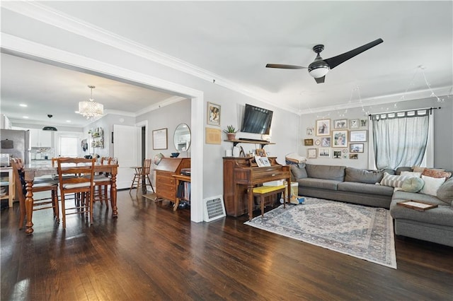 living room with visible vents, ornamental molding, ceiling fan with notable chandelier, and wood finished floors